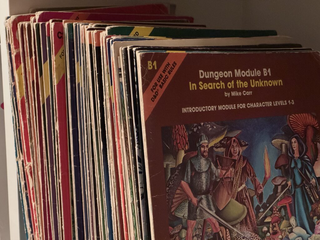 About fifty old D&D adventure booklets on a shelf, with Dungeon Module B1: In Search of the Unknown at the front.